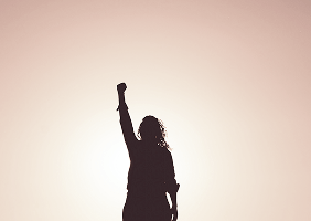 Silhouette einer Person mit erhobenem Arm vor hellem Hintergrund.